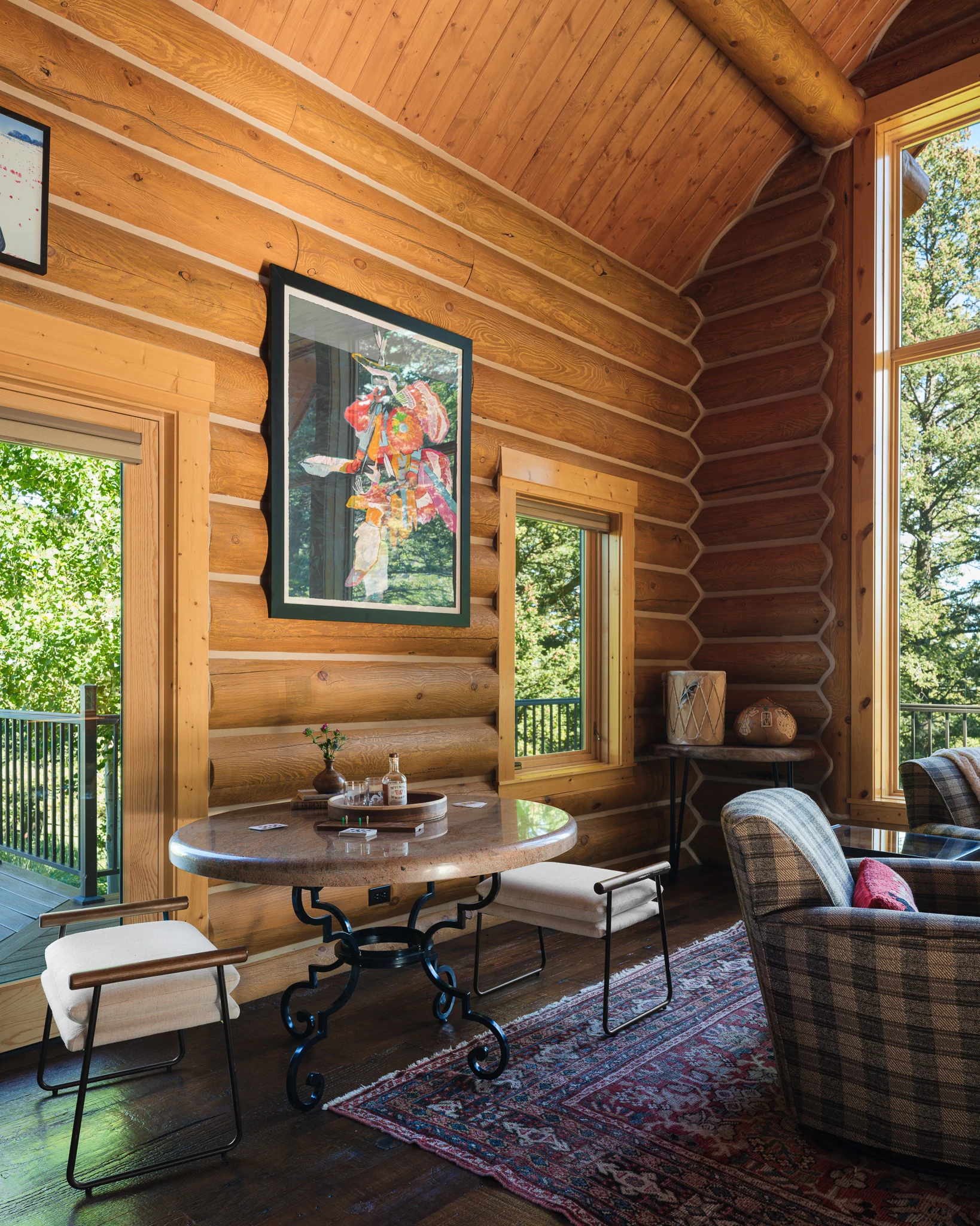 Sitting nook with round iron table and framed artwork against log walls — interior design photography Livingston Montana, Bear Canyon Ranch